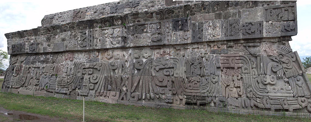 Ancien mur de pierre à Xochicalco avec des figures de serpents à plumes sculptées, montrant l'art préhispanique détaillé dans le site archéologique du Mexique.