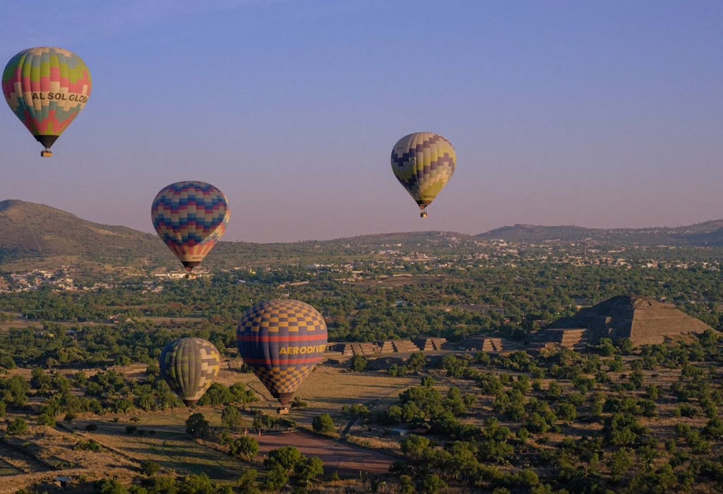 Montgolfières colorées survolant les pyramides de Teotihuacan, au Mexique, au lever du soleil, offrant une vue imprenable sur les ruines anciennes et le paysage de la vallée.