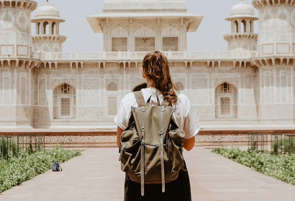 Traveler with a backpack standing in front of a beautiful historic building with detailed architecture, enjoying a cultural sightseeing moment.