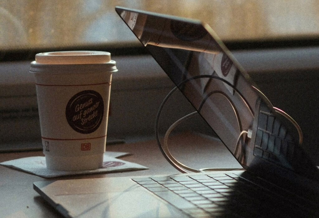 Open laptop and coffee cup on a train table, showing a moment of work and travel on the go.