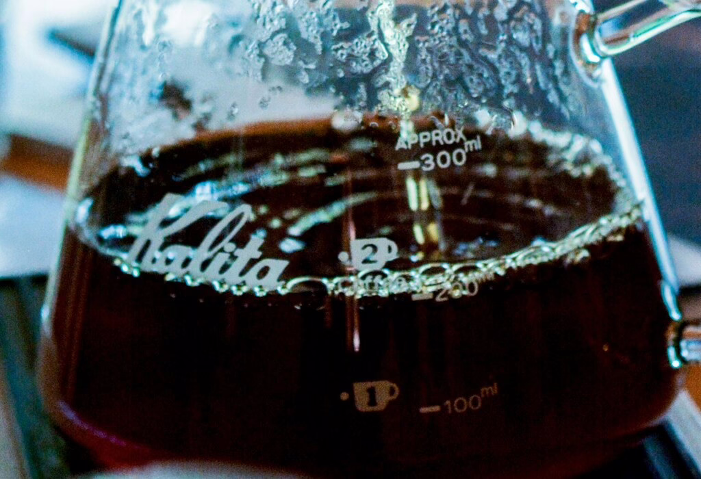 Glass beaker filled with hot brewed coffee, showing dark rich color.
