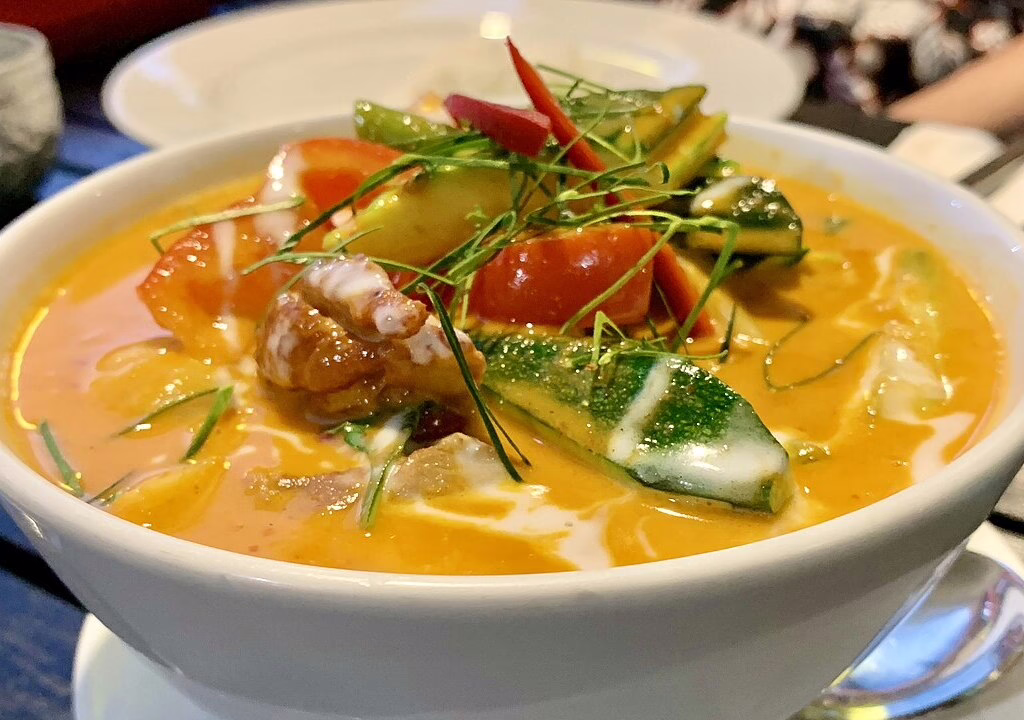 A bowl of Thai laksa with fresh vegetables, showcasing Singapore cuisine's vibrant and rich flavors.