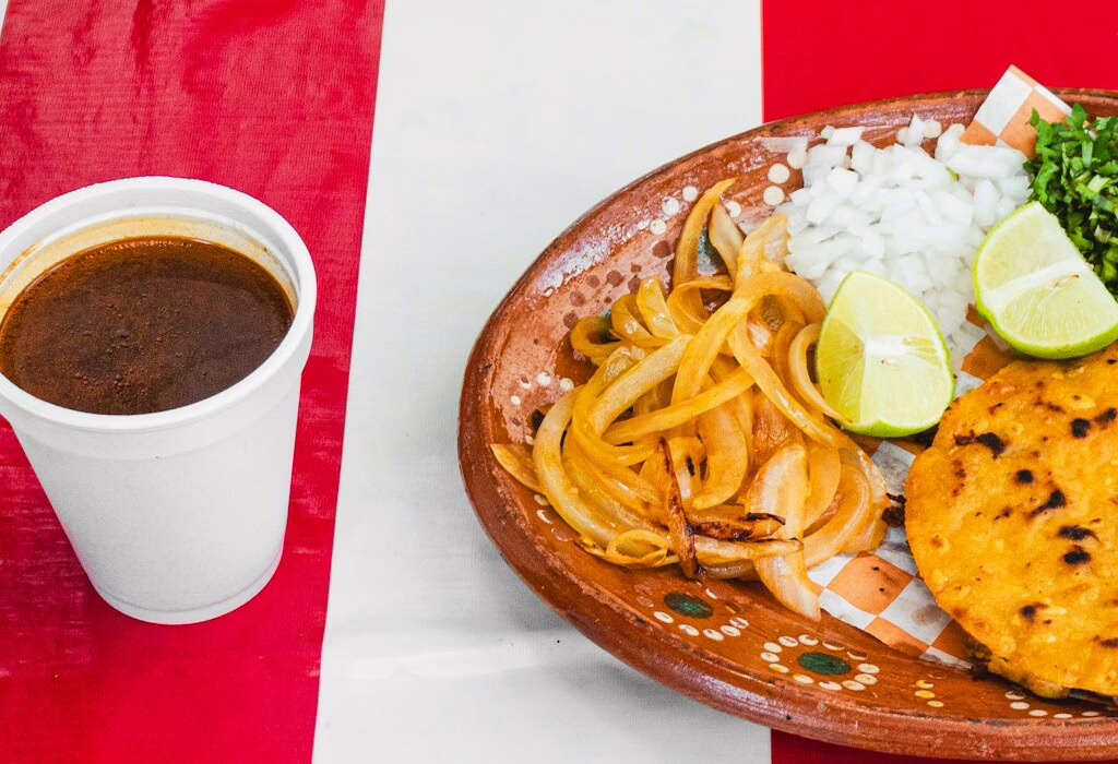 Traditional Mexican food from Jalisco served with lime, onion, cilantro, and a cup of broth, perfect for tasting authentic flavors and local traditions.