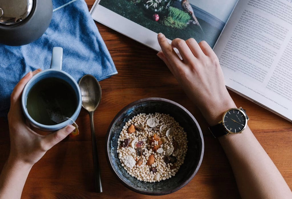 A cozy morning with a warm cup of tea, a bowl of healthy cereal, and a magazine on a wooden table, perfect for relaxation.