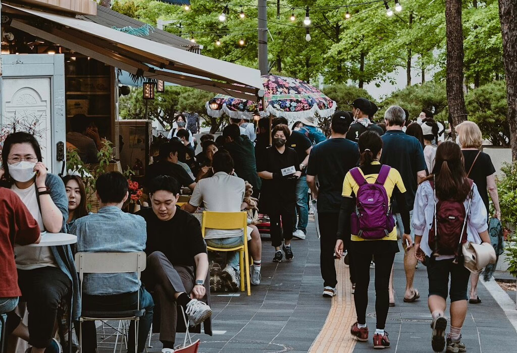 A busy street with people walking and enjoying outdoor cafes in a vibrant urban setting.