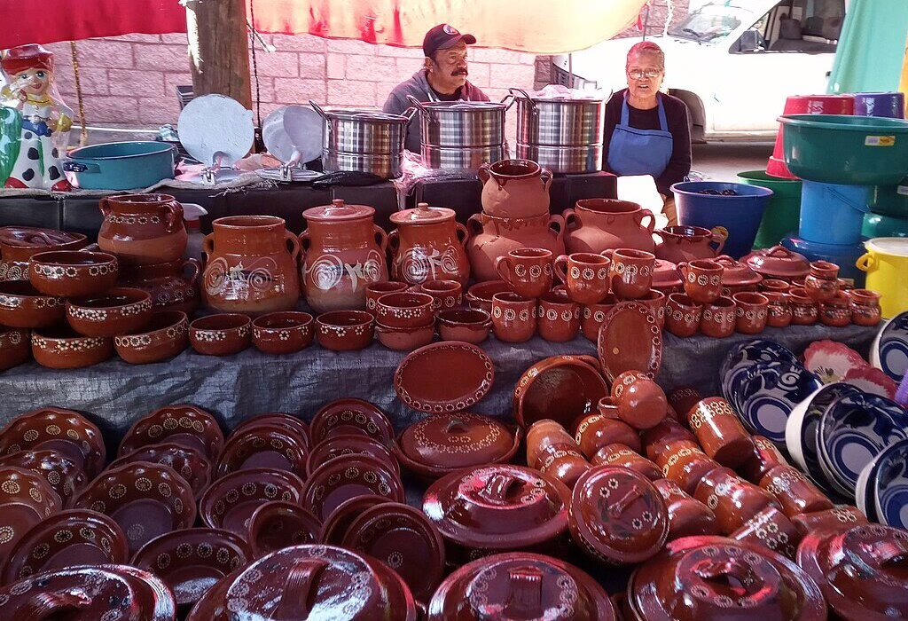 Pottery for sale at a lively tianguis market in Aguascalientes. Traditional clay dishes are displayed, showcasing local craftsmanship.