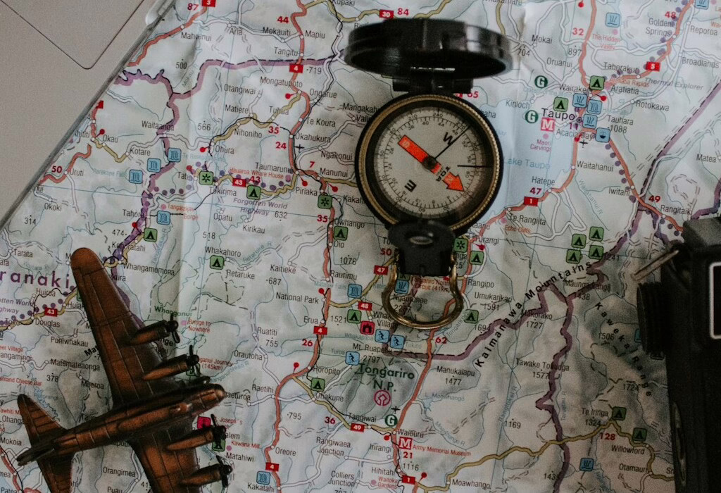 A travel compass placed on a detailed map with a vintage airplane model, symbolizing exploration, navigation, and adventure through beautiful landscapes.