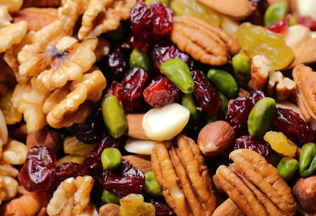 Close-up of mixed nuts and dried fruits travel snack—walnuts, pecans, pistachios, almonds, cranberries, raisins—healthy energy for road trips, flights, hikes, and long days exploring.