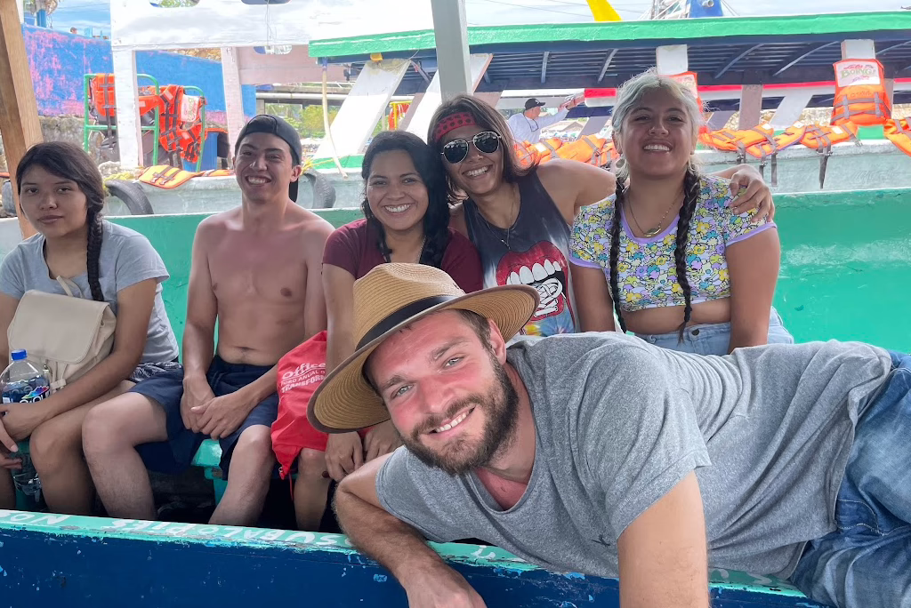 A group of tourists enjoying a boat ride in Acapulco, smiling and posing for a picture in the bright sunshine.