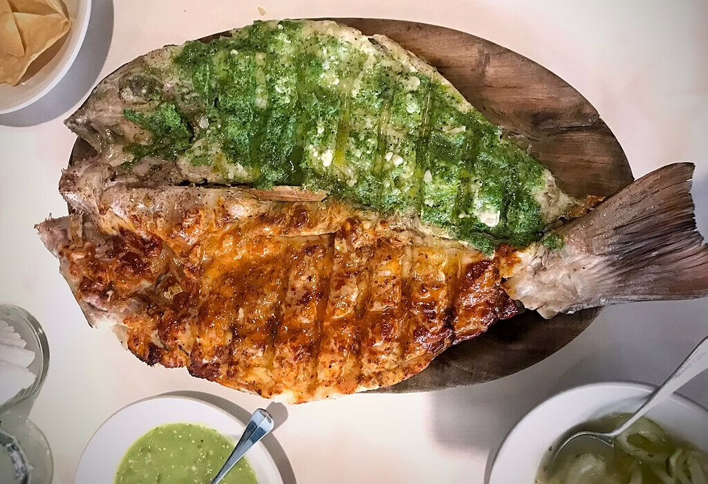 A delicious grilled fish platter served with green and red salsas, showcasing a local Acapulco specialty for seafood lovers.