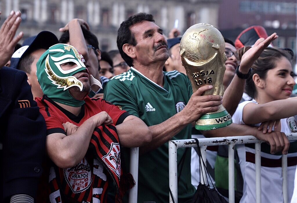 Torcedores mexicanos comemorando o futebol com o troféu da copa do mundo e máscaras durante a copa do mundo do méxico evento cheio de cor e energia