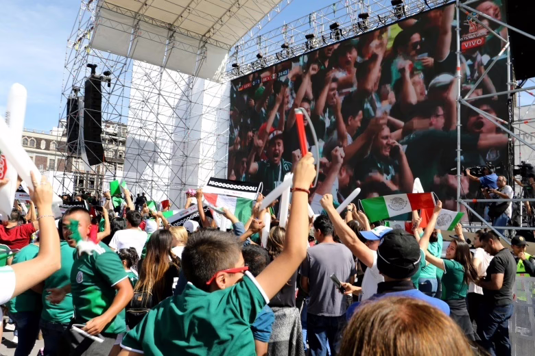 Muitos fãs de futebol torcendo juntos em uma praça para o evento da Copa do Mundo do México.