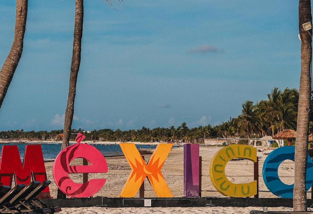 Colorful &ldquo;Mexico&rdquo; sign on a beach with palm trees, a welcoming and safe destination in Mexico for travelers