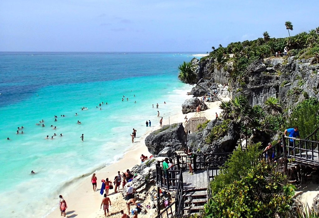 Cliffside beach in Tulum with turquoise water and visitors enjoying the shore, a safe destination in Mexico for travelers