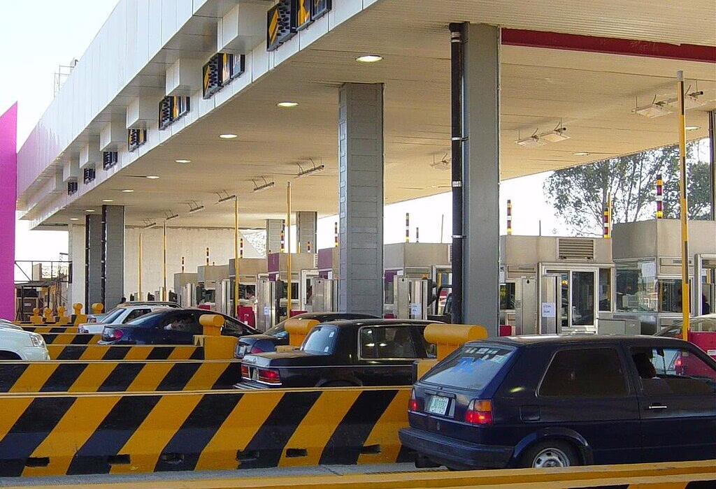 Several cars lined up at a highway toll booth station in Mexico, showing the infrastructure for traveling between Mexico City and nearby lake destinations.