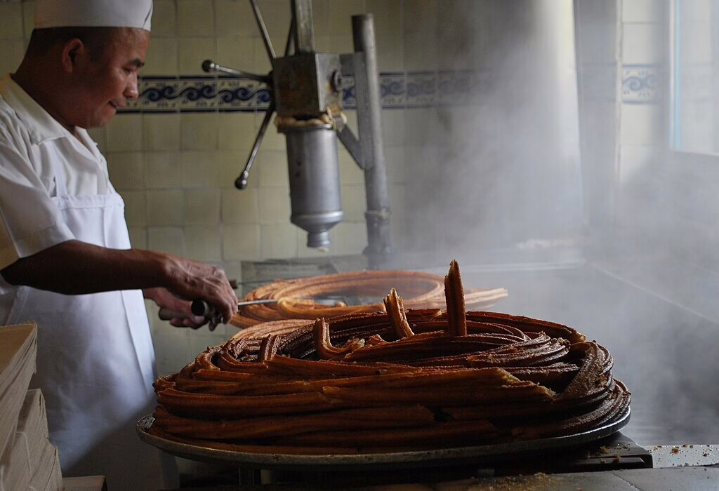 Man cooking sweet churros in El Moro churreria in Mexico City Historic Center