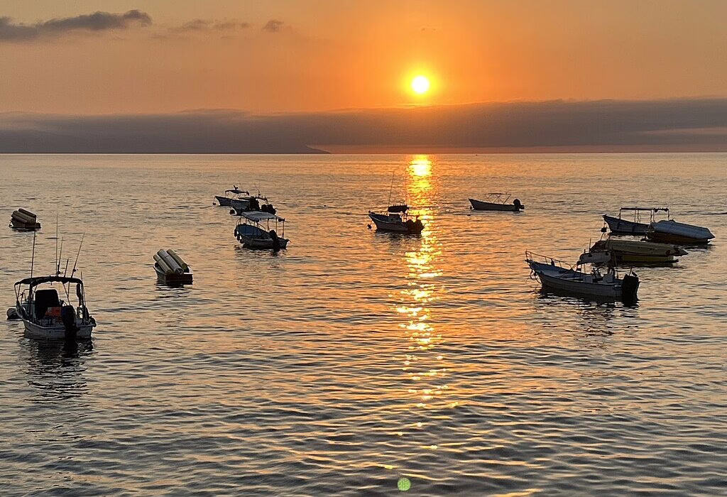Sunset over the Pacific Ocean in Puerto Vallarta with small boats, the main gateway for tours to Marietas Islands Hidden Beach