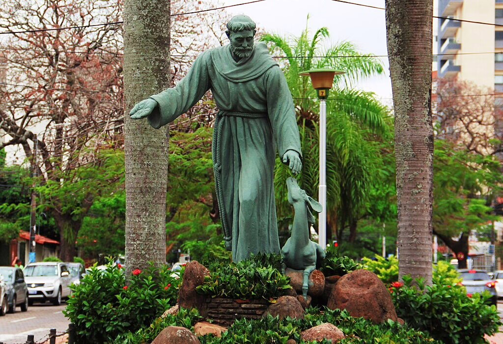 Statue of St. Francis of Assisi with a deer, symbolizing his love for nature, in a peaceful public space, a tribute to his spirituality and connection with animals