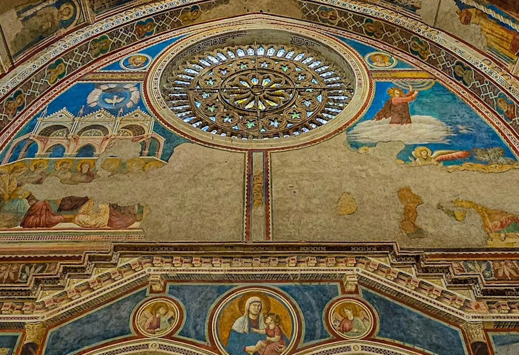 The beautiful frescoes and rose window inside the Basilica of St. Francis of Assisi, a stunning example of medieval art depicting divine figures and heavenly scenes