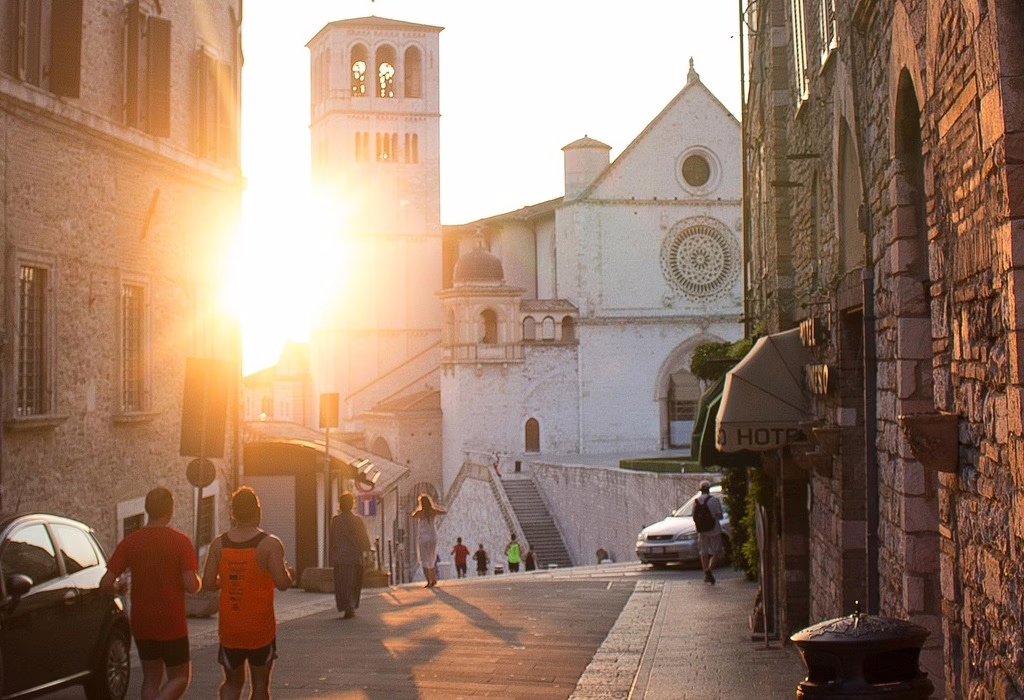 Sunset view of the Basilica of St. Francis of Assisi, with its iconic bell tower and traditional rooftops, reflecting the beauty and history of Assisi in Italy. (cathedral basilica of st francis of assisi photos)