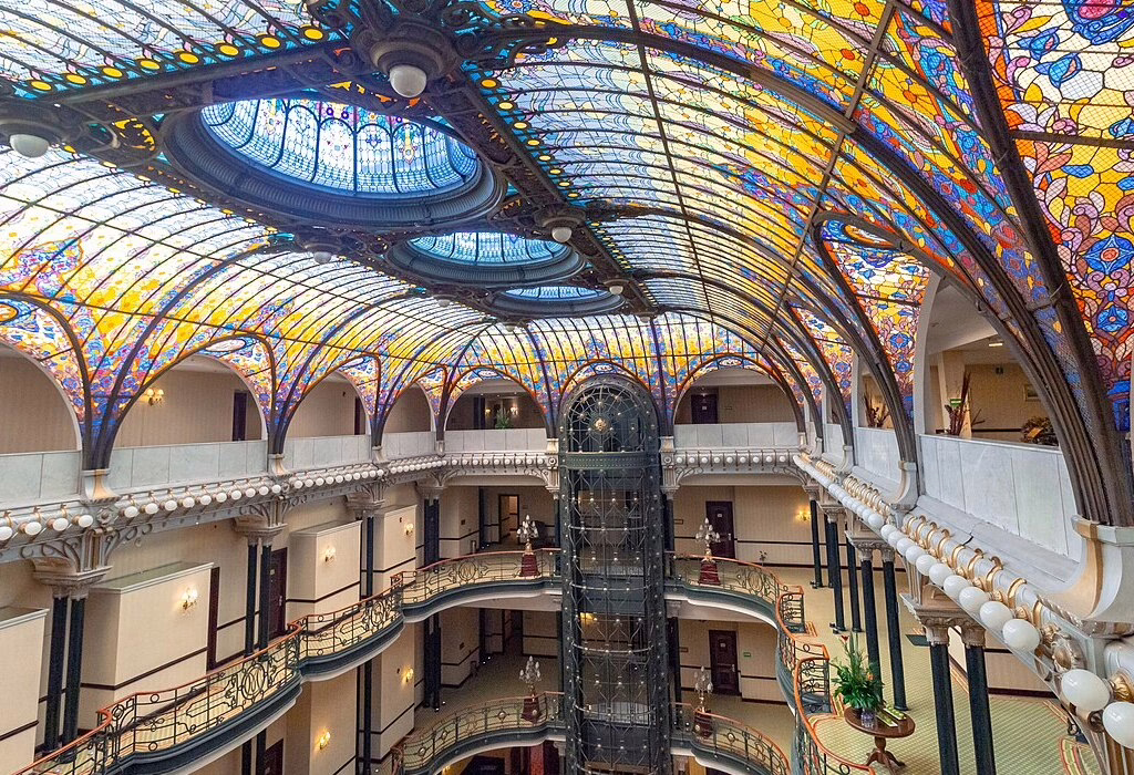 Interior of the luxury Gran Hotel Ciudad de México, featuring its famous tiffany stained-glass roof. This level of luxury represents the expensive side of the city center, making it hard to find hostels in Mexico City and affordable hotels in mexico city nearby.