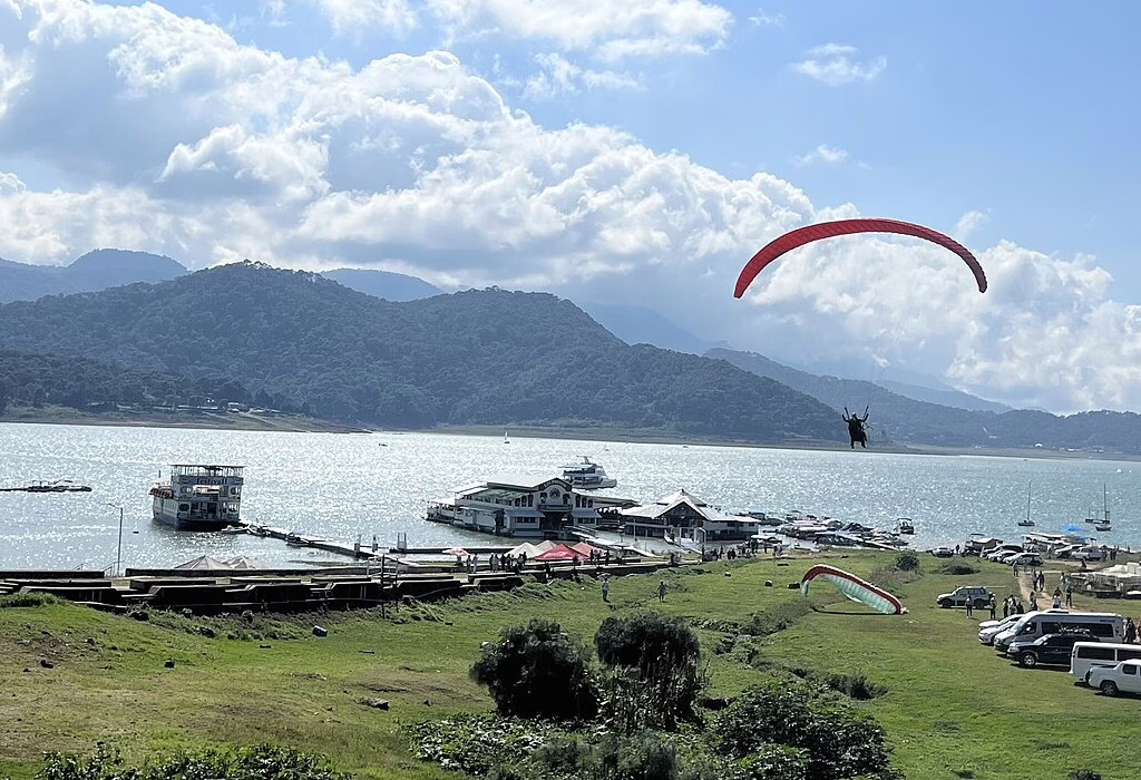 View of a paraglider flying over the lake in Valle de Bravo, perfect for day trips from Mexico City.