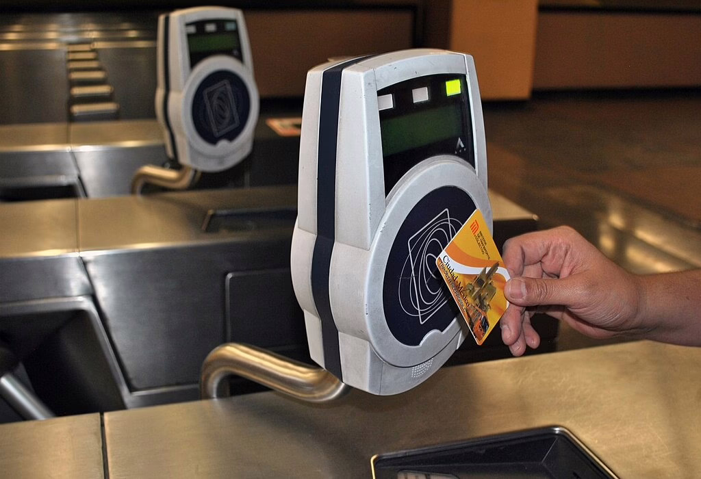 Person tapping a transport card at a Mexico City Metro turnstile.