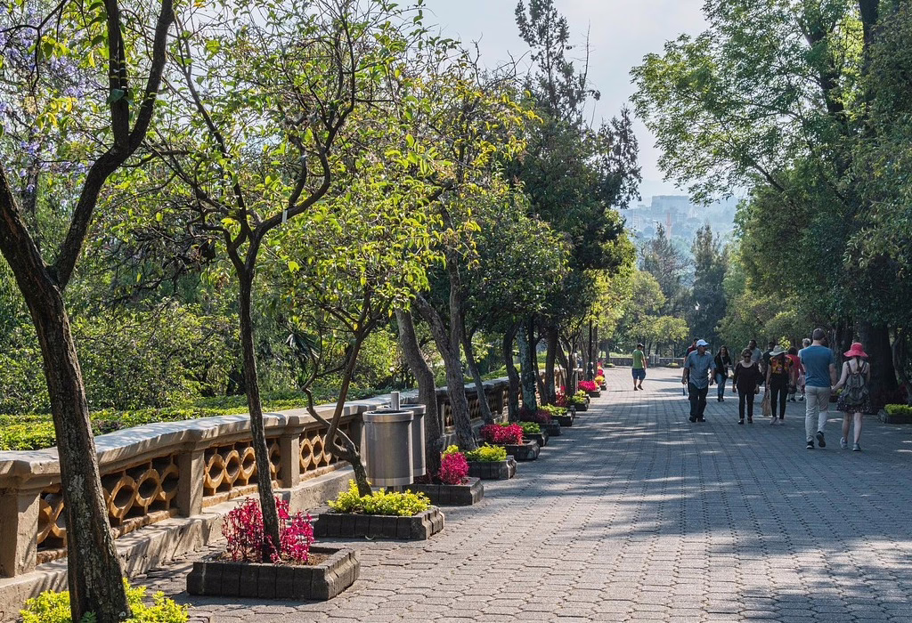 People walking on a sunny path in Chapultepec Park, a great spot for day trips from Mexico City.