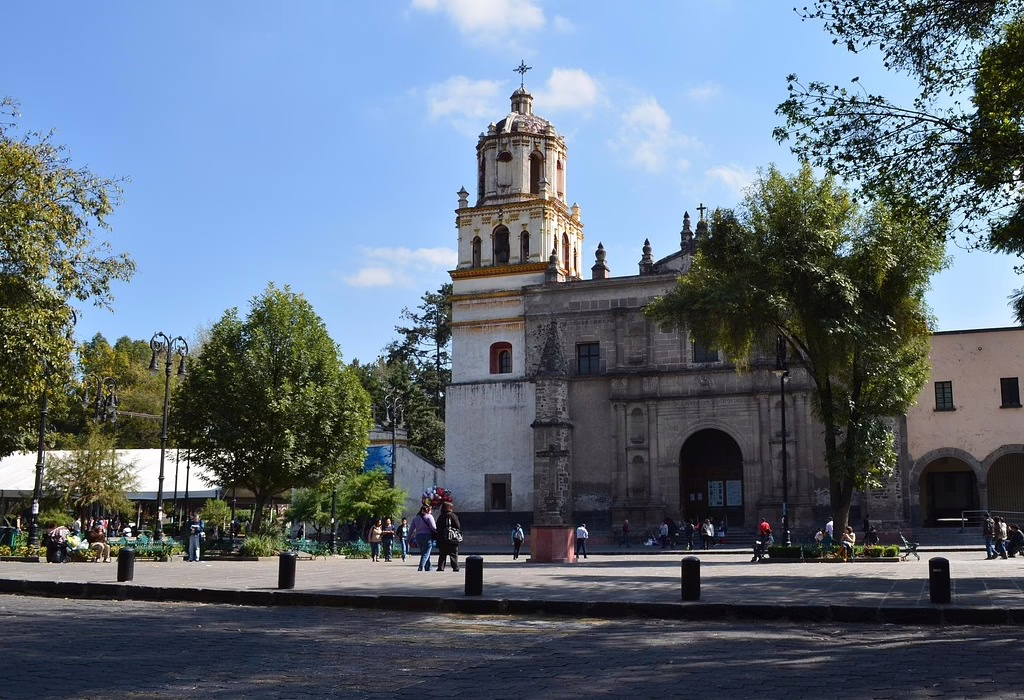 People walking in a sunny colonial plaza in Coyoacan, a neighborhood that illustrates why Mexico City is safe for tourists.