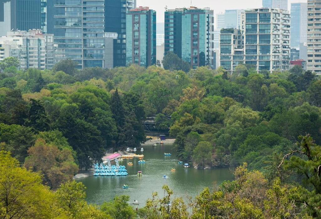 Ein malerischer Blick auf den See im Chapultepec-Park mit der Skyline von Mexiko-Stadt, eine der besten kostenlosen Aktivitäten für günstige Reisen nach Mexiko.