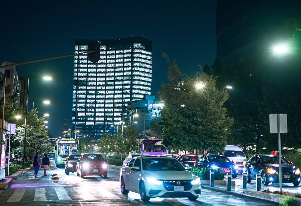 Traffic flows on a well-lit night street in a safe Mexico City area, highlighting urban security.