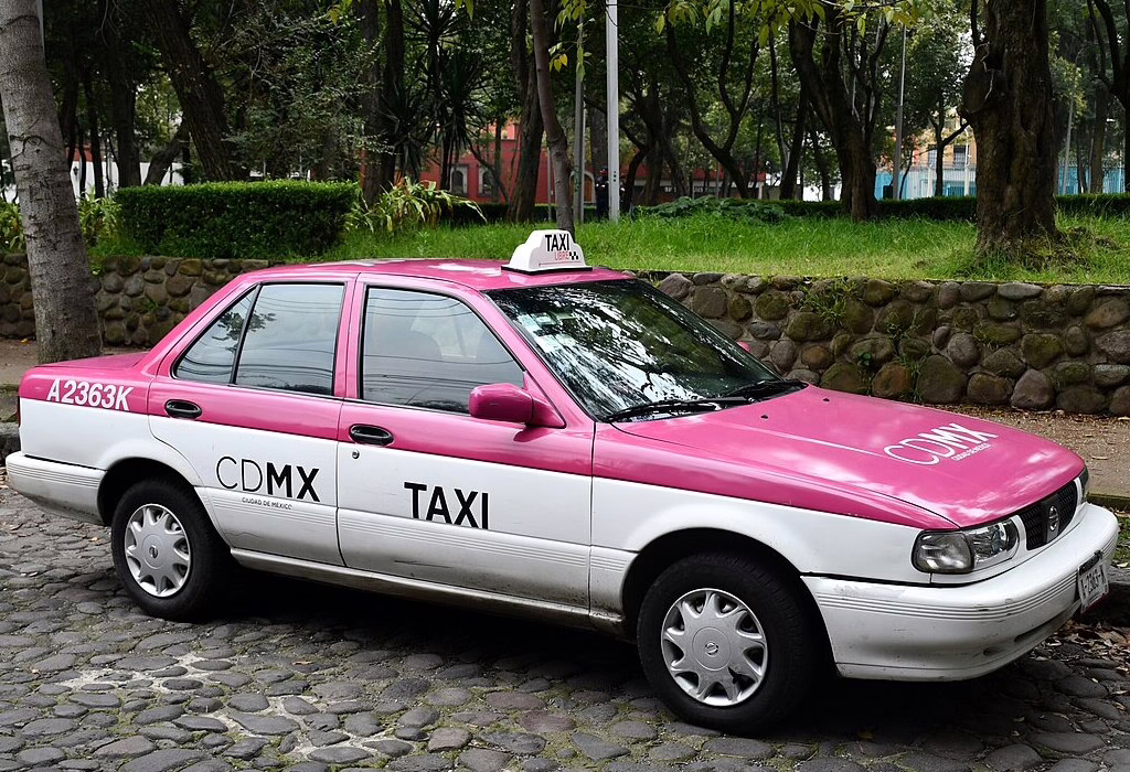 Pink and white official CDMX taxi in Mexico City.